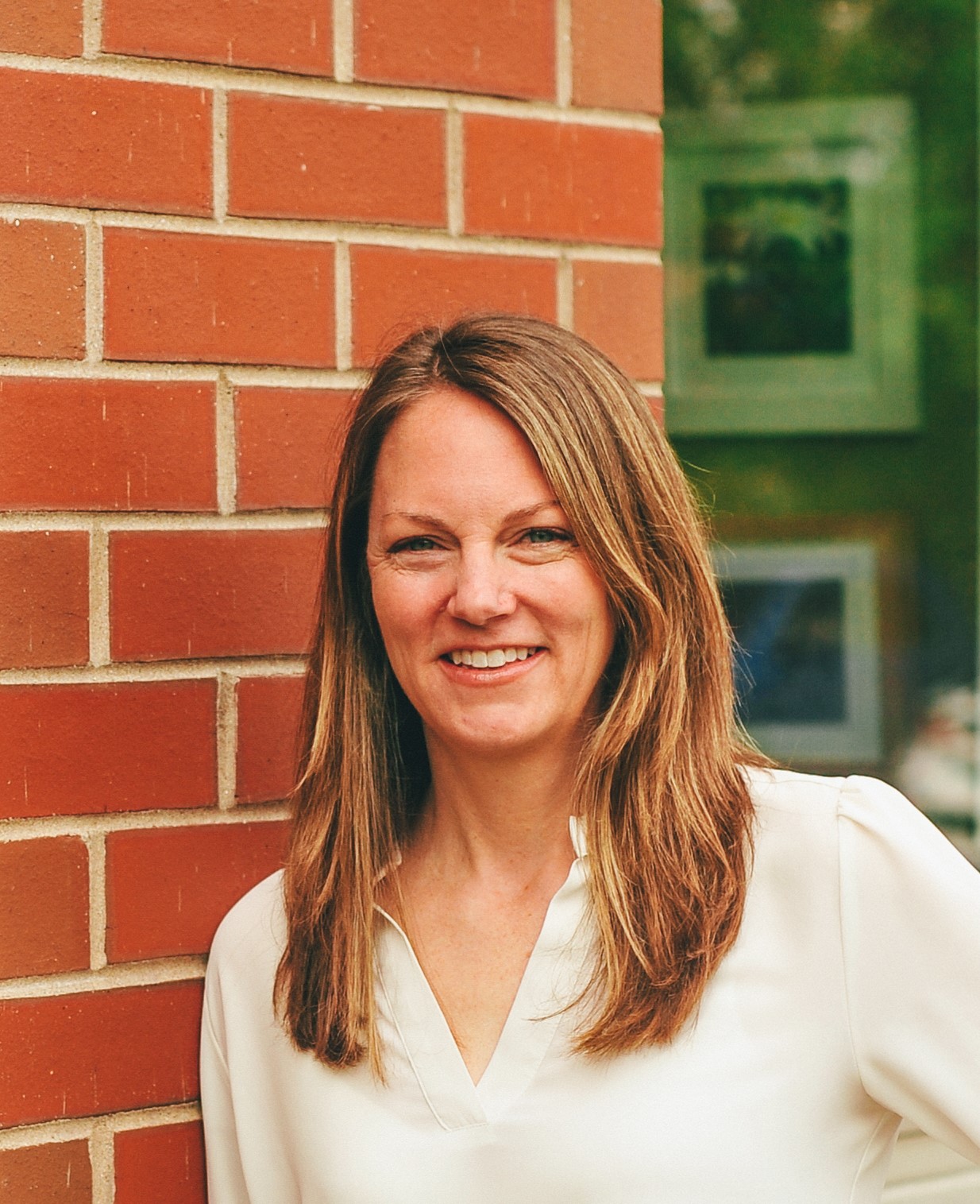 Photo of woman with long hair in front of brick building